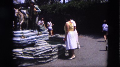 1963: two old women stand near to sculpture in park where present many tourists