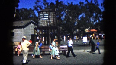 1963: parents and their young children walk around in public area near building.