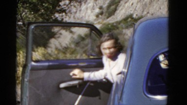 1952: women exits car driving pacific coast highway road. CALIFORNIA