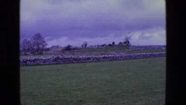 1969: a beautiful stone fence with a grassy foreground and a cloudy dark sky