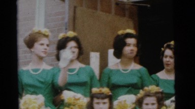 1963: four women in green and four men in black and white standing together