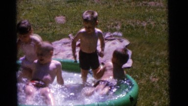 1963: a group of children splashing in a portable pool on a sunny day CAMDEN,