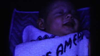 1961: baby laying down on bed being tickled by father in the dark DETROIT