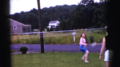 1961: a group of men and women playing badminton in a big green backyard.