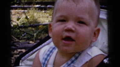 1961: babbling baby boy in vintage stroller in wooded park DETROIT, MICHIGAN