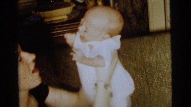 1961: mother giving kiss and hug to the infant crying baby at home. DETROIT