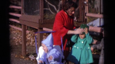 1963: women is fixing a child's hats. she is with three young infant and they