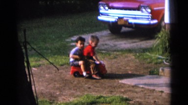 1963: two cute little boys playing on a big red toy truck in the yard CAMDEN