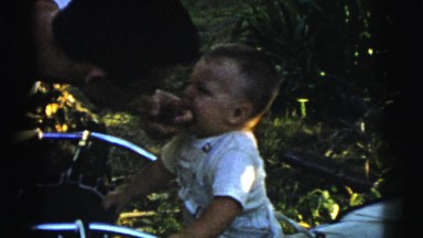 1961: little boy biting and playing with arm and hand of a man and a small ball