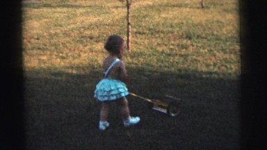 1961: boy and girl playing with lawnmower toys on a field DETROIT, MICHIGAN