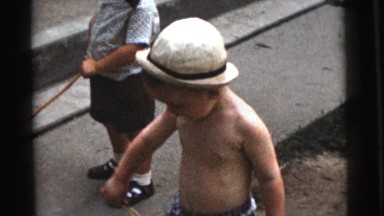 1961: boy shows off his scooter as his younger brothers play in the grass