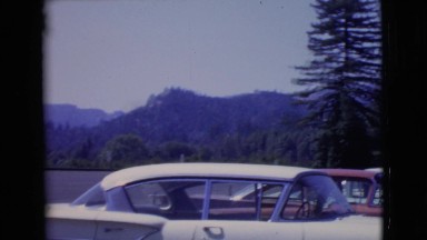 1968: tall trees and a clear sky surround a somewhat filled parking lot