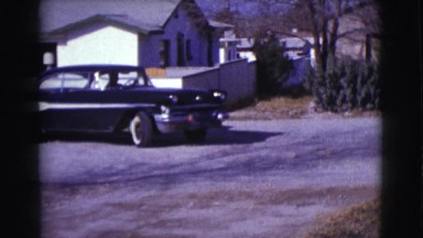 1961: One Person in an Old Black Car with White Stripe Backing Up and Pulling Out