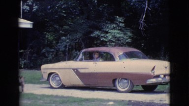 1961: a woman in a hat and glasses is backing her car out of her driveway