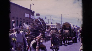 1961: people in various costumes marching through the street in a parade
