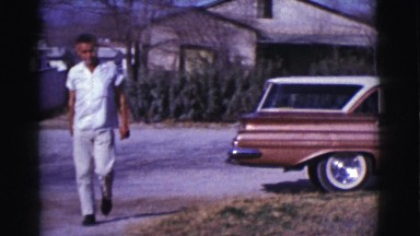 1961: two men in and around the driveway of a home, with one of them driving