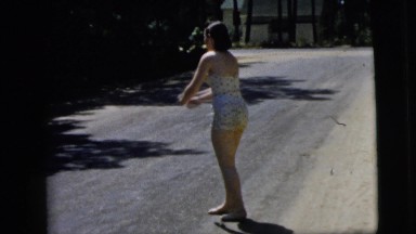 1962: barefoot woman throws ball dusty road sand sunny day 1950s-1960s