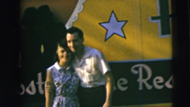 1962: happy couple pose for a snap in front of large banner CAMDEN, NEW JERSEY
