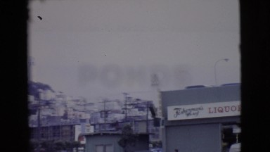 1968: a city street on the base of a hill with homes on it with a tall building