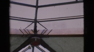 1968: woman views a winter outdoor chapel covered with snow and foliage