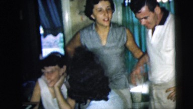 1962: group of people celebrating with unopened champagne in a kitchen CAMDEN