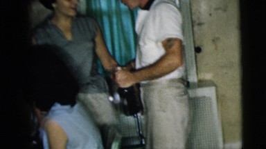 1962: a handsome man holding a bottle while flirting with a pretty woman
