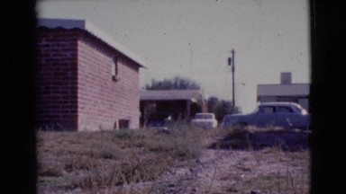 1964: low brick houses with high wooden fencing and scrubby, vacant land