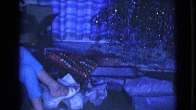 1968: a young boy crosses in front of a christmas tree toward a seated woman