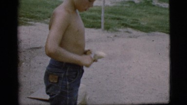 1968: a cute shirtless boy outside using a knife to peel a potato COTTONWOOD