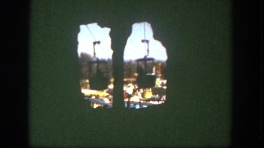 1962: people ride aerial tramway through elevated tunnel in an amusement park.