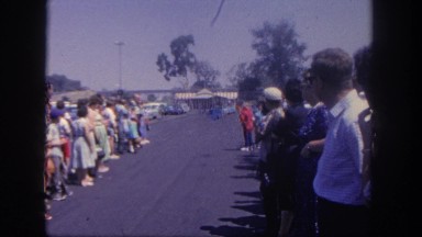 1962: people lined up in a parking lot awaiting an arriving tour train