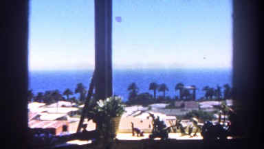 1962: picturesque seaside view from a hotel window of blue ocean and trees