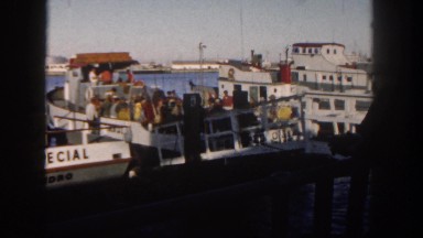 1962: a large boat filled with people docked on the water in a harbor