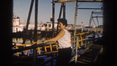 1962: a woman on a deck looking out over the water and boats in the harbor