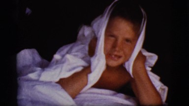 1968: two children on the floor are wrapped up in sheets as they wake up