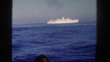 1962: older gentleman and ladies on boat watching cruise ship go by on the water
