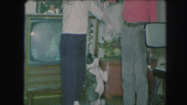 1958: three people playing with a dog at christmas time. AMES, IOWA