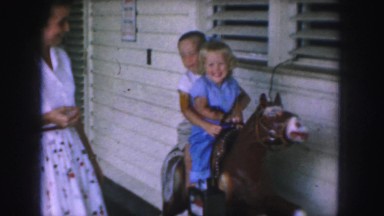 1958: two children ride on a mock horse and mother enjoys AMES, IOWA