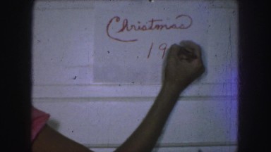 1958: someone writing christmas 1957 on a piece of paper tacked to the wall