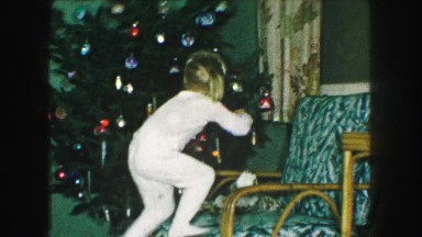 1958: little blonde girl hangs christmas ornament on christmas tree AMES, IOWA