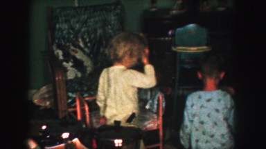 1958: children in pajamas examining their christmas gifts under the tree AMES