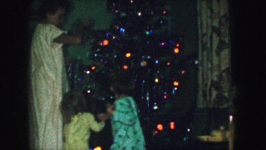 1958: mother and children decorating vintage christmas tree in home AMES, IOWA