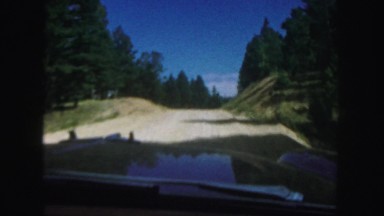 1958: truck slowly curves up dirt hill in the mountains with a beautiful scenery