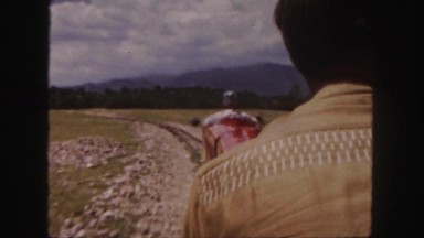 1958: a man is riding a small, red train operated by an engineer