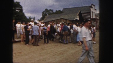 1958: in a western town, two cowboys cart a dead body in a wheelbarrow through