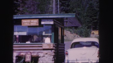1958: a driver pays the toll at an entrance booth to a mountain attraction.