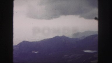 1958: huge gray cloud looming over scenic mountain range threatening storms