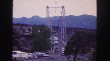 1958: vehicles and pedestrians are going in to cross a tall and imposing