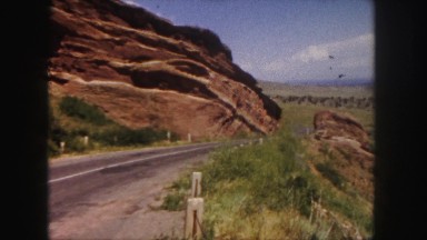1958: red rocks denver area classic car driving past monoliths. COLORADO