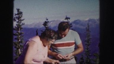 1958: a man and woman outside with a breathtaking view of the rugged mountains